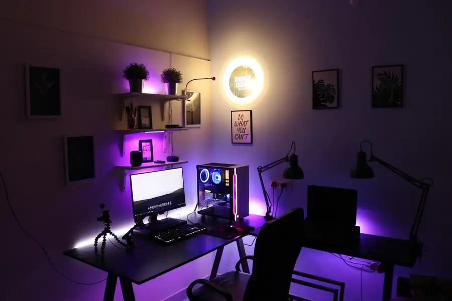 Mesa de jogo com comandos e ecrã iluminado em tons de néon